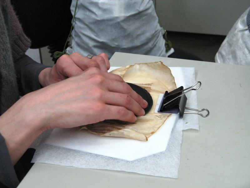 9. Flattened and stretched, a first clip holds the folio to a board and a weight is applied (Ms. 83).